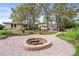 Backyard featuring a fire pit with seating, grass, mature trees, garden beds, and detached garage at 2020 Routt St, Lakewood, CO 80215