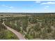 A scenic aerial shot showcases a home nestled among lush trees with a winding driveway, in a country setting at 1972 Gold Camp Way, Franktown, CO 80116