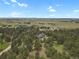 Expansive aerial view captures a lovely home surrounded by lush trees with scenic fields in the background at 1972 Gold Camp Way, Franktown, CO 80116