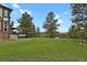 Expansive backyard with lush greenery, mature trees, and a gentle slope leading towards the home at 1972 Gold Camp Way, Franktown, CO 80116