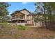 Rear exterior view featuring a large home with a multi-tiered deck surrounded by rocks and native vegetation at 1972 Gold Camp Way, Franktown, CO 80116