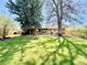 This backyard features large trees, green grass and brick home at 5563 E Jefferson Ave, Denver, CO 80237