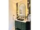 Stylish bathroom features an ornate, emerald green vanity, black fixtures, and an arched mirror at 5563 E Jefferson Ave, Denver, CO 80237
