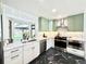 Bright kitchen features white countertops, sage green cabinets, stainless steel appliances, and eye-catching black marble floors at 5563 E Jefferson Ave, Denver, CO 80237