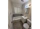 Standard bathroom with white fixtures, gray and white tile, and a window with blinds above the bathtub at 1717 Oswego St, Aurora, CO 80010