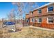 Exterior shot of a fenced yard, landscaping, and the brick home at 2823 Jasmine St, Denver, CO 80207