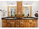 Bathroom with a wooden double vanity, dual mirrors, and black countertops at 8216 S Tempe Ct, Aurora, CO 80016