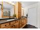 Bathroom with a wooden double vanity, dual mirrors, and black countertops at 8216 S Tempe Ct, Aurora, CO 80016