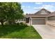 Inviting home exterior featuring a well-kept lawn, a two-car garage, stone accents, and a charming entryway at 8216 S Tempe Ct, Aurora, CO 80016