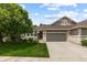 Charming home with a well-manicured front lawn, mature tree, and a two-car garage at 8216 S Tempe Ct, Aurora, CO 80016