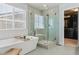 Modern bathroom features a glass-enclosed shower and a soaking tub by a large window at 13822 Worthington Pl, Parker, CO 80134