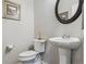 Well-maintained half-bathroom with a pedestal sink, toilet, and decorative mirror at 13822 Worthington Pl, Parker, CO 80134