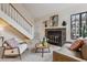 Comfortable living room featuring a brick fireplace, staircase, and ample natural light, creating a welcoming space at 836 S Vance St # E, Lakewood, CO 80226