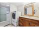 Bright bathroom featuring a washer and dryer next to a vanity and a shower with glass doors at 9700 E Iliff Ave # G70, Denver, CO 80231