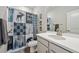 Well-lit bathroom with a decorative shower curtain, modern vanity, and a large mirror at 14373 Shasta Daisy Pt, Parker, CO 80134