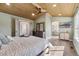 Airy bedroom showcasing a wood-paneled ceiling, ceiling fan, large window, and view into the bathroom at 1534 Stanley Dr, Erie, CO 80516