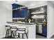 Stylish wet bar featuring dark blue cabinetry, black countertops and backsplash, and bar seating at 6037 N Netherland Ct, Aurora, CO 80019