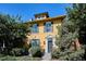 Charming yellow two-story home featuring classic architectural details, shuttered windows, and lush landscaping at 263 N Logan St, Denver, CO 80203