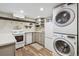 Modern kitchen and laundry area featuring gray cabinets, stainless steel appliances, and stacked washer/dryer units at 263 N Logan St, Denver, CO 80203