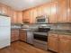 Kitchen featuring wood cabinets, stainless steel appliances, granite countertops, and wood flooring at 13618 E Bethany Pl # 306, Aurora, CO 80014
