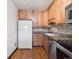 Kitchen features wood cabinets, stainless steel appliances, granite countertops, and wood flooring at 13618 E Bethany Pl # 306, Aurora, CO 80014