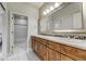 This bathroom features double sinks with wood cabinets and tile flooring at 4181 S Ivy Ln, Cherry Hills Village, CO 80111