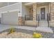 Close-up of a home's entrance with stone accents, a black metal railing, and a well-kept front yard with gravel and plants at 4769 Weitbrec Ln, Castle Rock, CO 80104