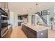 Modern kitchen featuring a large island with bar seating, stainless steel appliances, and access to the living room and staircase at 4769 Weitbrec Ln, Castle Rock, CO 80104