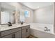 Bright bathroom featuring double sinks, quartz countertops, and a soaking tub at 9454 Yampa St, Commerce City, CO 80022