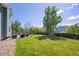A fenced yard with a lush lawn and an outdoor seating area on a stone patio at 12277 Krameria St, Brighton, CO 80602