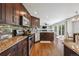Modern kitchen featuring stainless appliances, granite countertops, dark cabinets, and wooden floors at 12277 Krameria St, Brighton, CO 80602