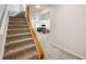 Carpeted staircase leading down to a finished basement with a seating area at 12277 Krameria St, Brighton, CO 80602