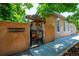 Unique Santa Fe-style home exterior with a rustic wooden gate, adobe walls and mature trees at 807 9Th St, Golden, CO 80401