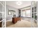 Bright office space with a built-in window seat, shelves, and a dark wood desk viewed through French doors at 3225 Rinn Valley Dr, Longmont, CO 80504