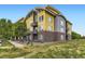 Modern condo building featuring a yellow and gray color scheme, brick accents, and private balconies at 8165 E Lowry Blvd # 310, Denver, CO 80230