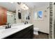 Bathroom featuring double sinks, modern lighting and a tiled shower at 6798 Depew St, Arvada, CO 80003