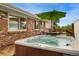 Inviting hot tub adjacent to a brick house with a wooden deck and green umbrella-covered table with chairs at 6798 Depew St, Arvada, CO 80003