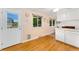 Bright kitchen area with hardwood floors, windows, and white cabinets at 6798 Depew St, Arvada, CO 80003