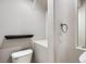 Compact powder room with a white toilet, dark shelf, towel ring, and textured walls at 7838 W Layton Way, Littleton, CO 80123