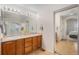 Bathroom featuring double sinks, wooden cabinets and an adjacent area with access to the primary bedroom at 15901 E 106Th Way, Commerce City, CO 80022