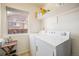 Bright laundry room features a side-by-side washer and dryer, convenient shelving, and natural light from a window at 15901 E 106Th Way, Commerce City, CO 80022