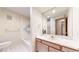 Bathroom featuring a tub with tile surround, vanity, and a round mirror at 23 Carla Way, Broomfield, CO 80020