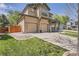 A view of a tan home highlighting a two-car garage and inviting front porch at 16376 Flintlock Ct, Parker, CO 80134