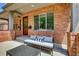 Charming front porch featuring a brick facade, a cozy daybed, and a decorative front door at 536 Cook St, Denver, CO 80206