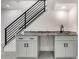 Close-up of wet bar in the finished basement with granite countertop and black fixtures near black metal stairs at 536 Cook St, Denver, CO 80206