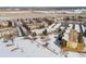 An aerial view of a condo community in winter with snow-covered lawns, tree cover, and adjacent covered parking at 9320 E Center Ave # 4B, Denver, CO 80247