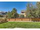 Well-maintained backyard with a green lawn, tall trees and a wooden fence at 10201 Rifle St, Commerce City, CO 80022