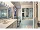 Retro bathroom features light blue tile, white marble vanity, and mirrored walls for a spacious feel at 3820 S Ames St, Denver, CO 80235