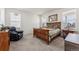 Bright bedroom with wood bed frame, a cozy sitting chair and two large windows at 15376 Ivanhoe Ct, Thornton, CO 80602