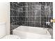 Bathtub with shower, marble tile surround, and silver fixtures at 2375 S Linden Ct # 201, Denver, CO 80222